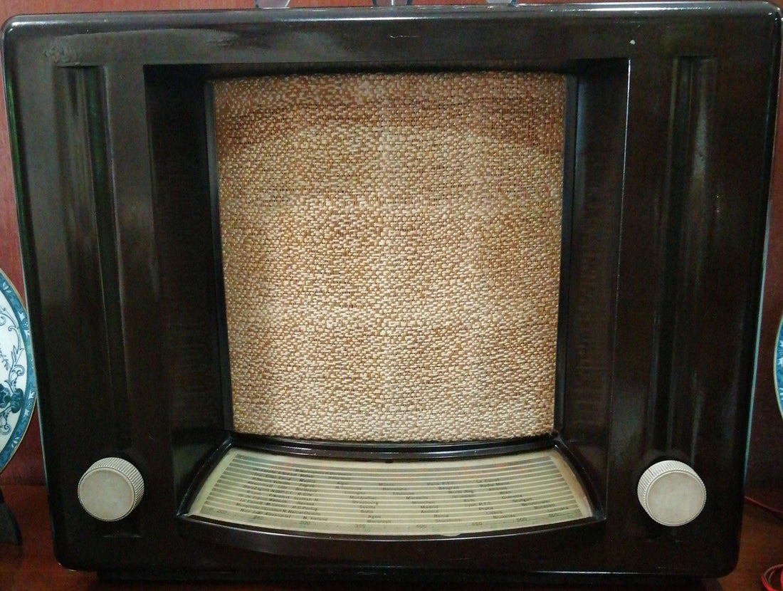 Radio de válvulas tipo teatro con carcasa de madera oscura y rejilla frontal de tela, auténtico estilo vintage para decoración clásica.