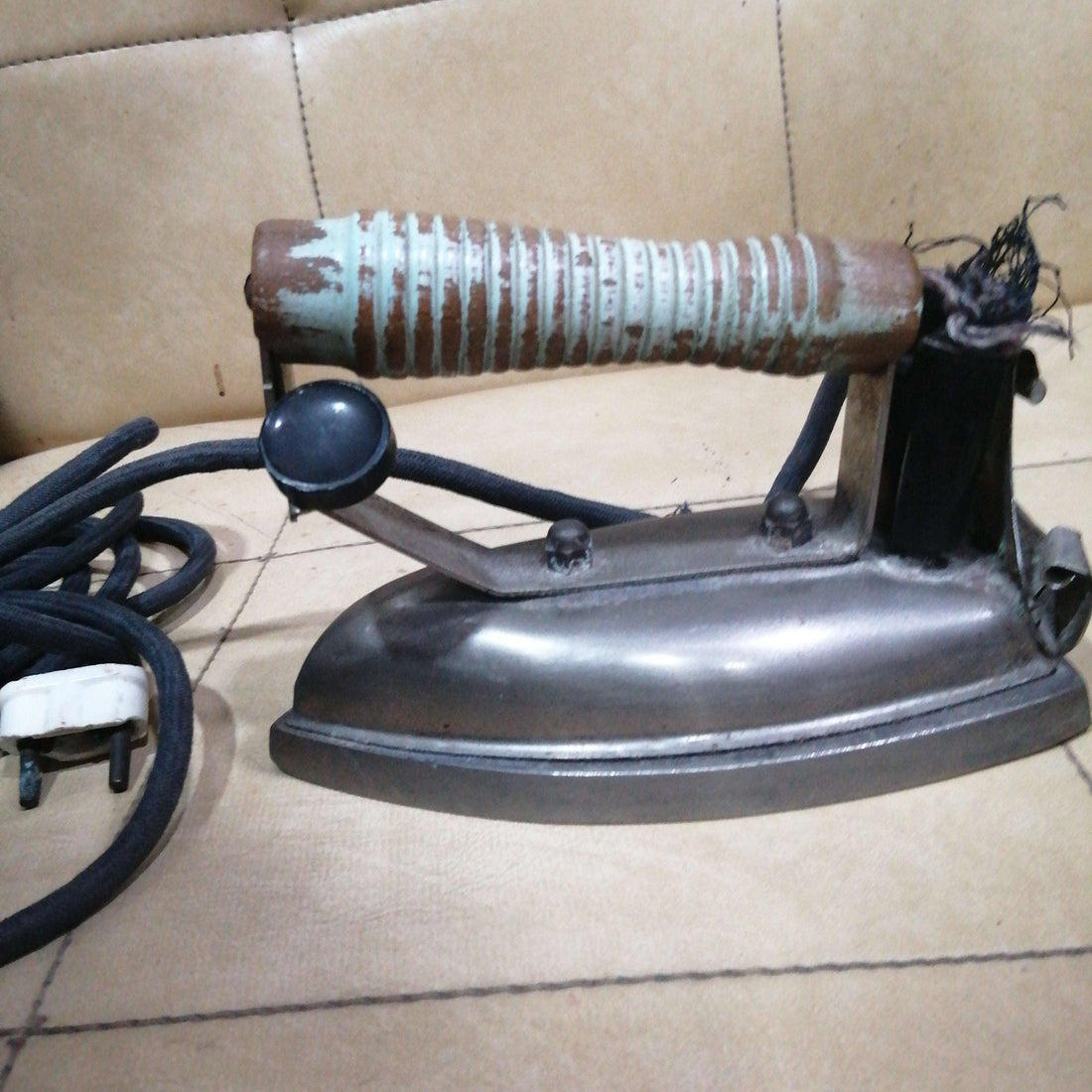 Plancha eléctrica antigua con mango de madera desgastado y cable textil, ideal para decoración vintage en hogar o colección retro.