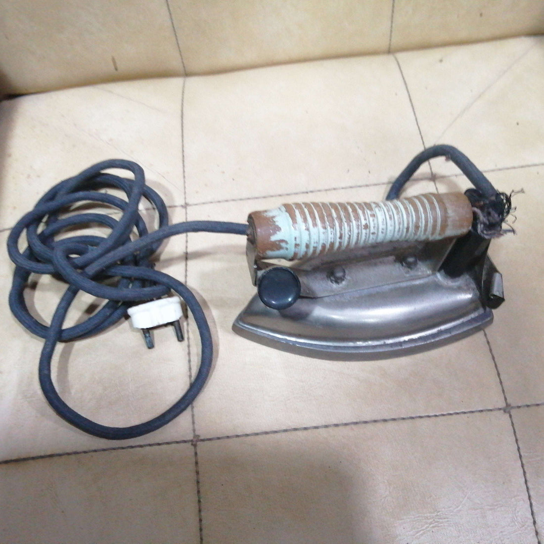 Plancha eléctrica antigua con mango de madera desgastado y cable textil, ideal para decoración vintage en hogar o colección retro.