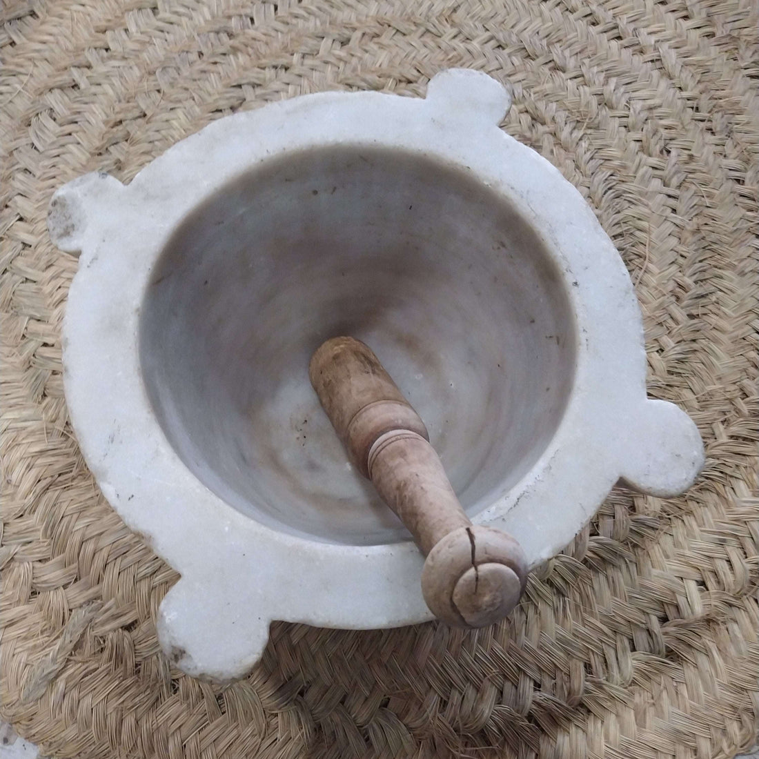 Mortero de mármol blanco antiguo con mazo de madera, ideal para decoración vintage en cocina o farmacia. Elegancia y precisión artesanal.