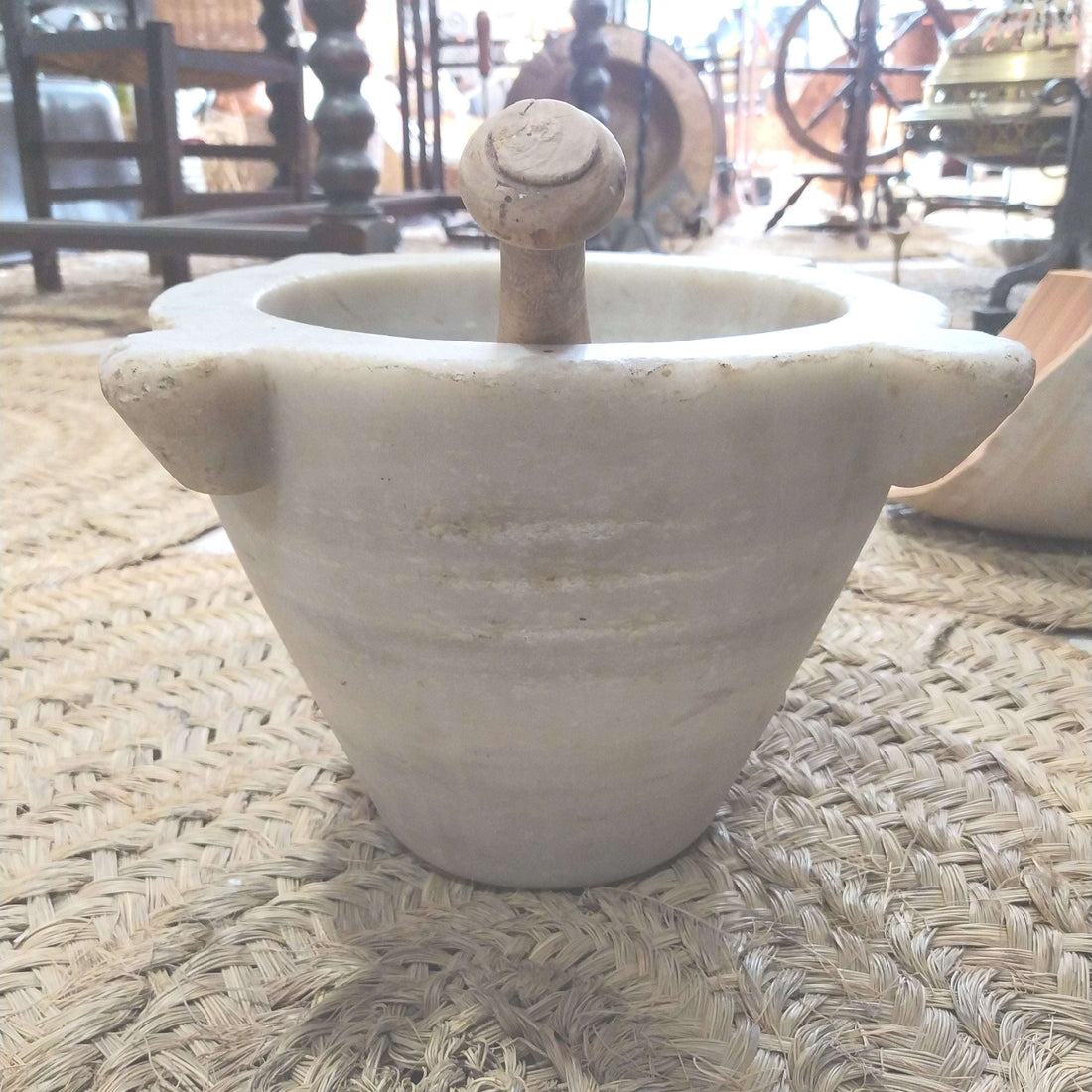 Mortero de mármol blanco antiguo con mazo de madera, ideal para decoración vintage en cocina o farmacia. Elegancia y precisión artesanal.