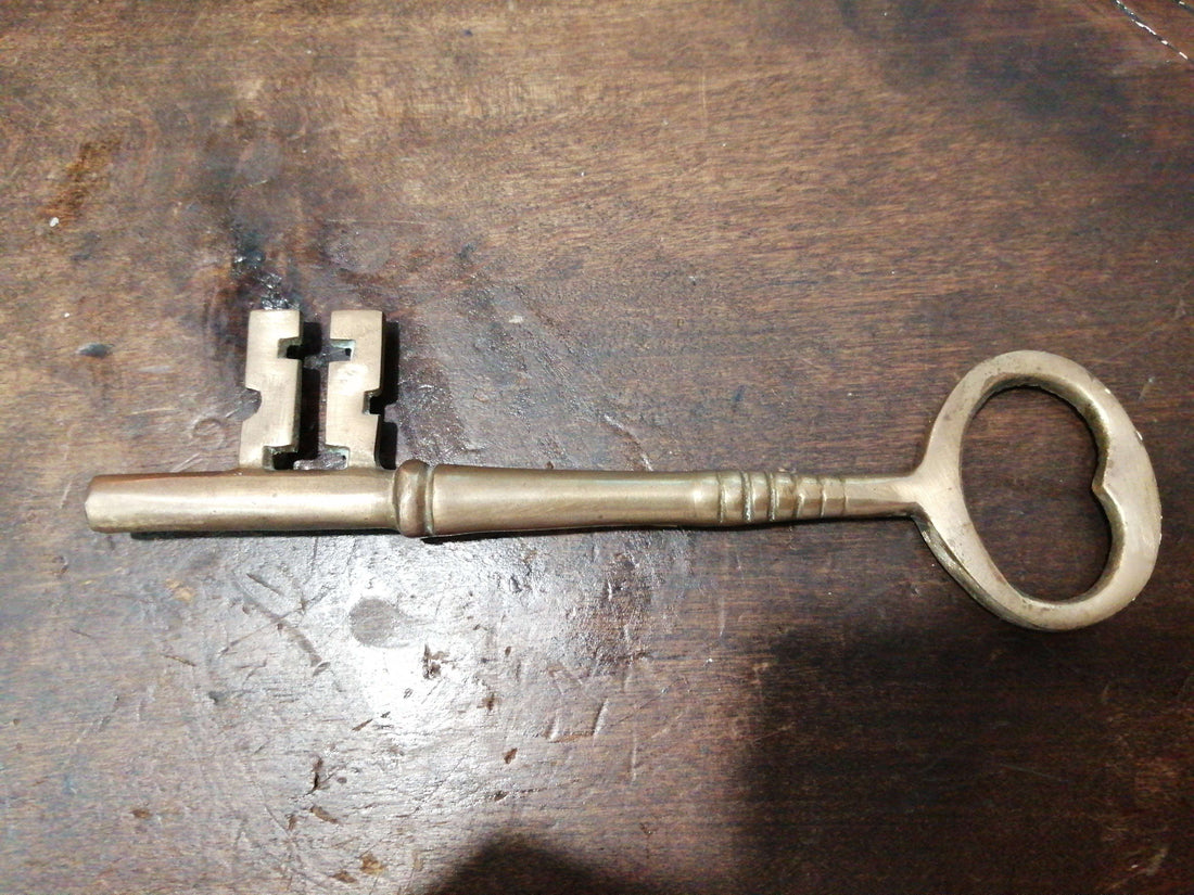 Llave antigua de hierro forjado, siglo XIX, con detalles únicos sobre superficie de madera. Ideal para decoración vintage en hogar o jardín.