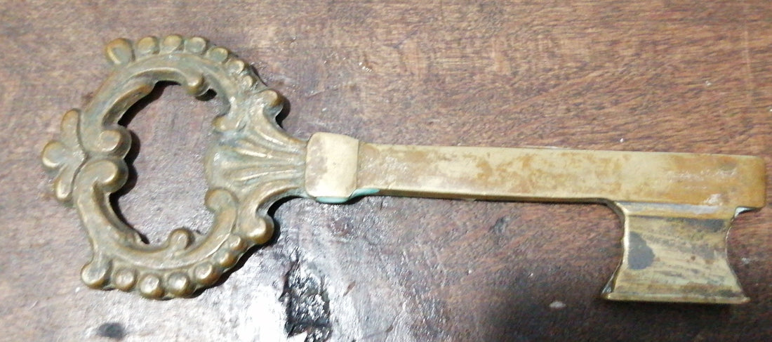 Llave antigua de bronce con detalles ornamentales sobre superficie de madera, ideal para decoración vintage en hogar o colección exclusiva.