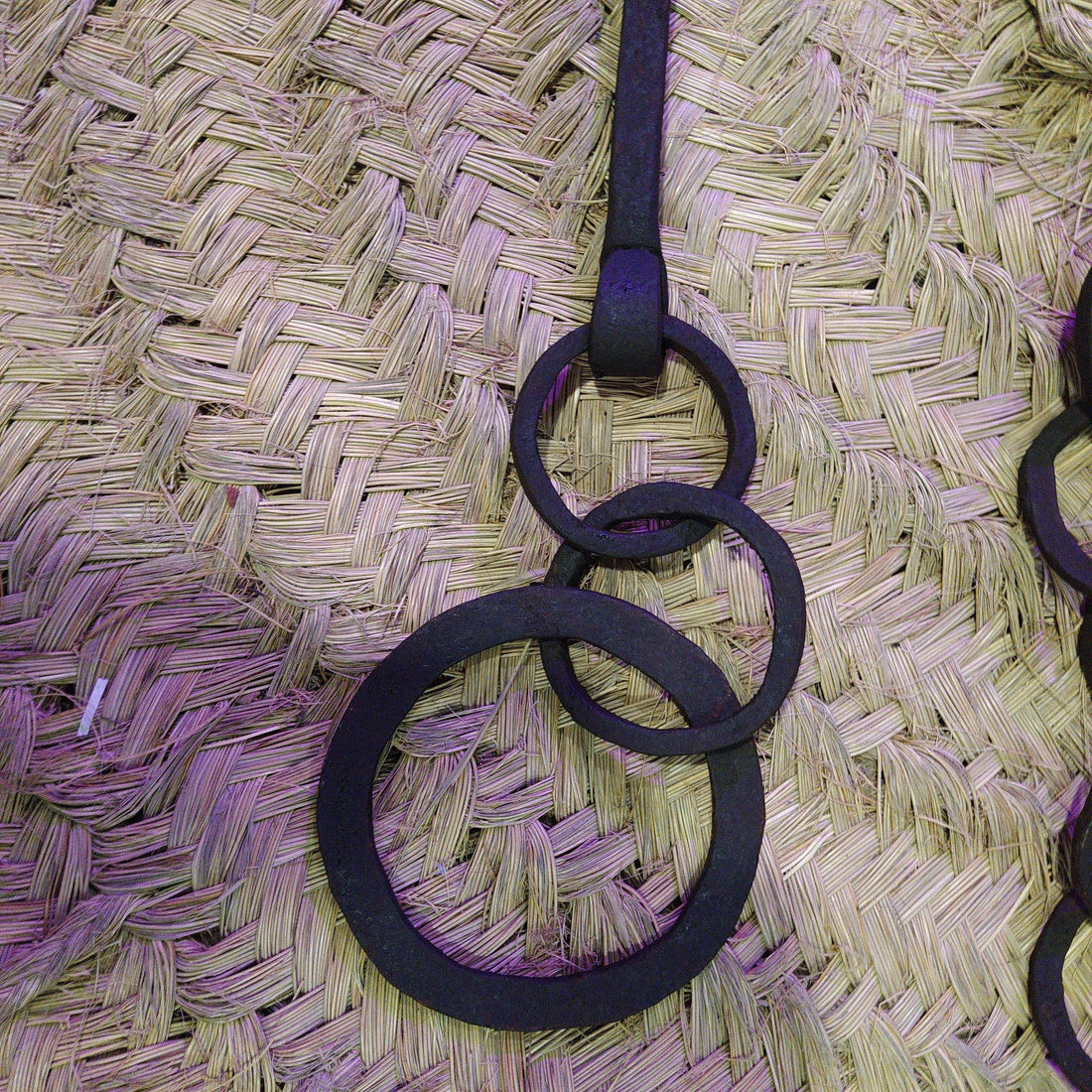 Cadena forjada - LLares de hierro forjado para colgar calderos sobre fondo de mimbre, ideal para decoración rústica de chimeneas.