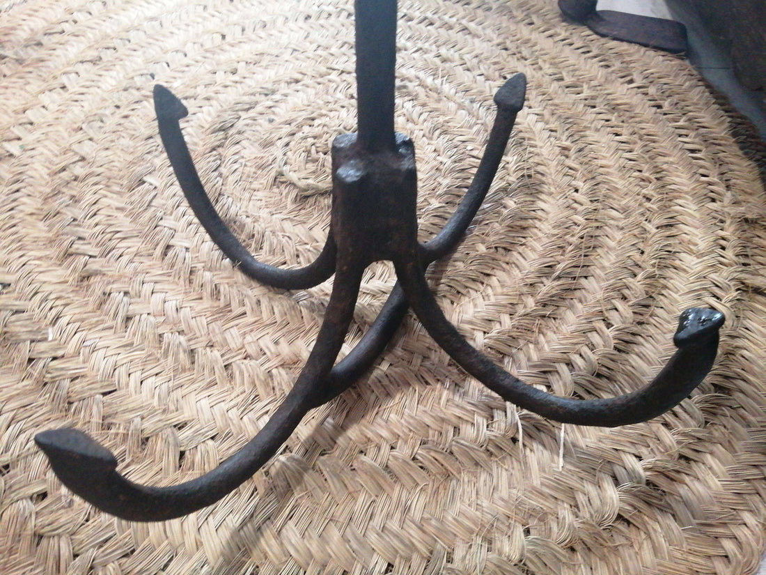 Ancla de hierro antigua con cuatro ganchos curvos, ideal como pieza decorativa náutica de excelente calidad para el hogar o jardín.