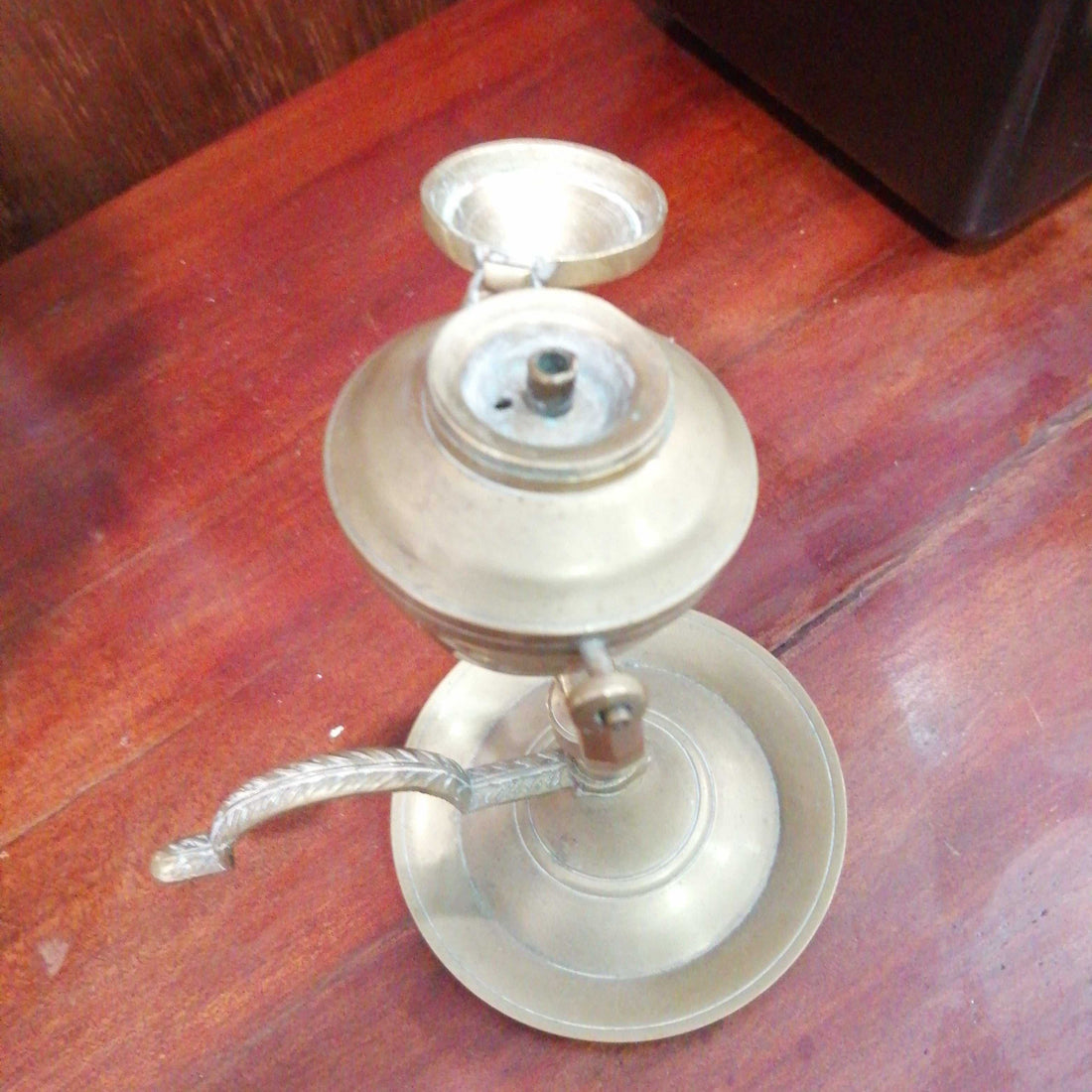 Candil antiguo de aceite en metal basculante de 17 cm sobre mesa de madera. Decoración vintage ideal para coleccionistas y amantes del estilo retro.