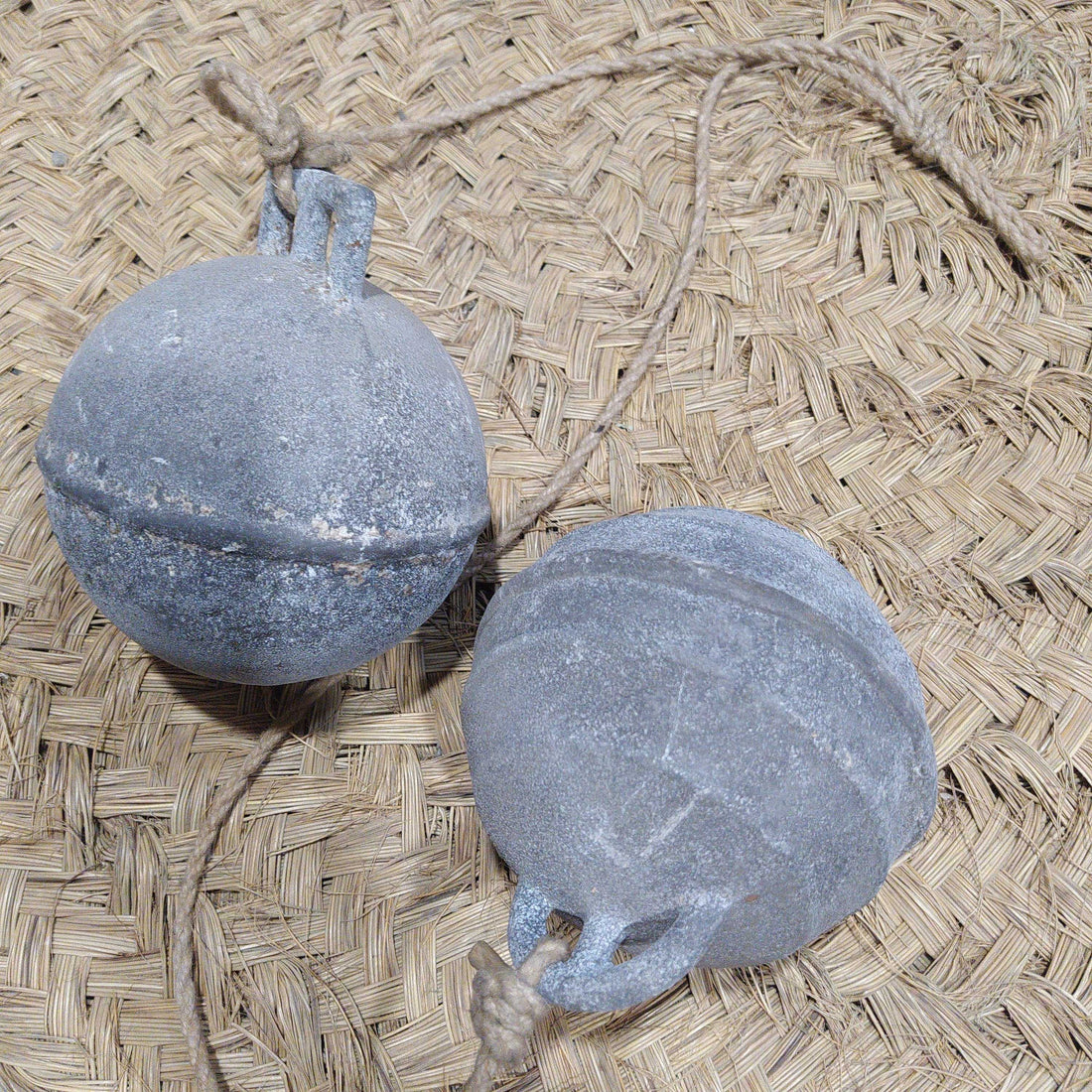 Boyas Náuticas de Calamina con acabado envejecido sobre fondo de fibra natural, ideales para decoración náutica vintage en el hogar o jardín.