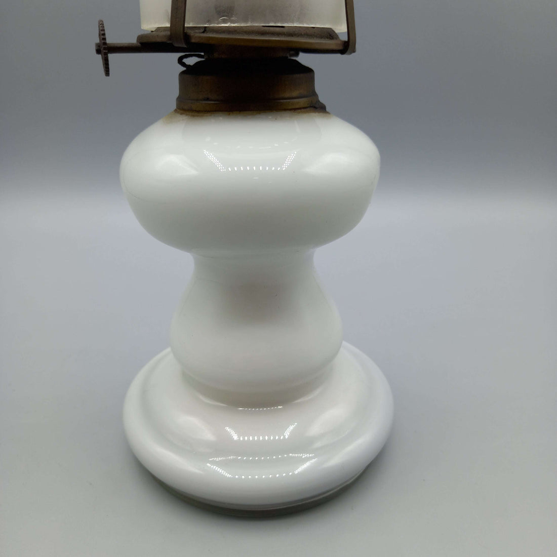 Quinqué de opalina antiguo blanco con base redonda y chimenea alta, ideal para decoración vintage en hogar. Iluminación de época exquisita.