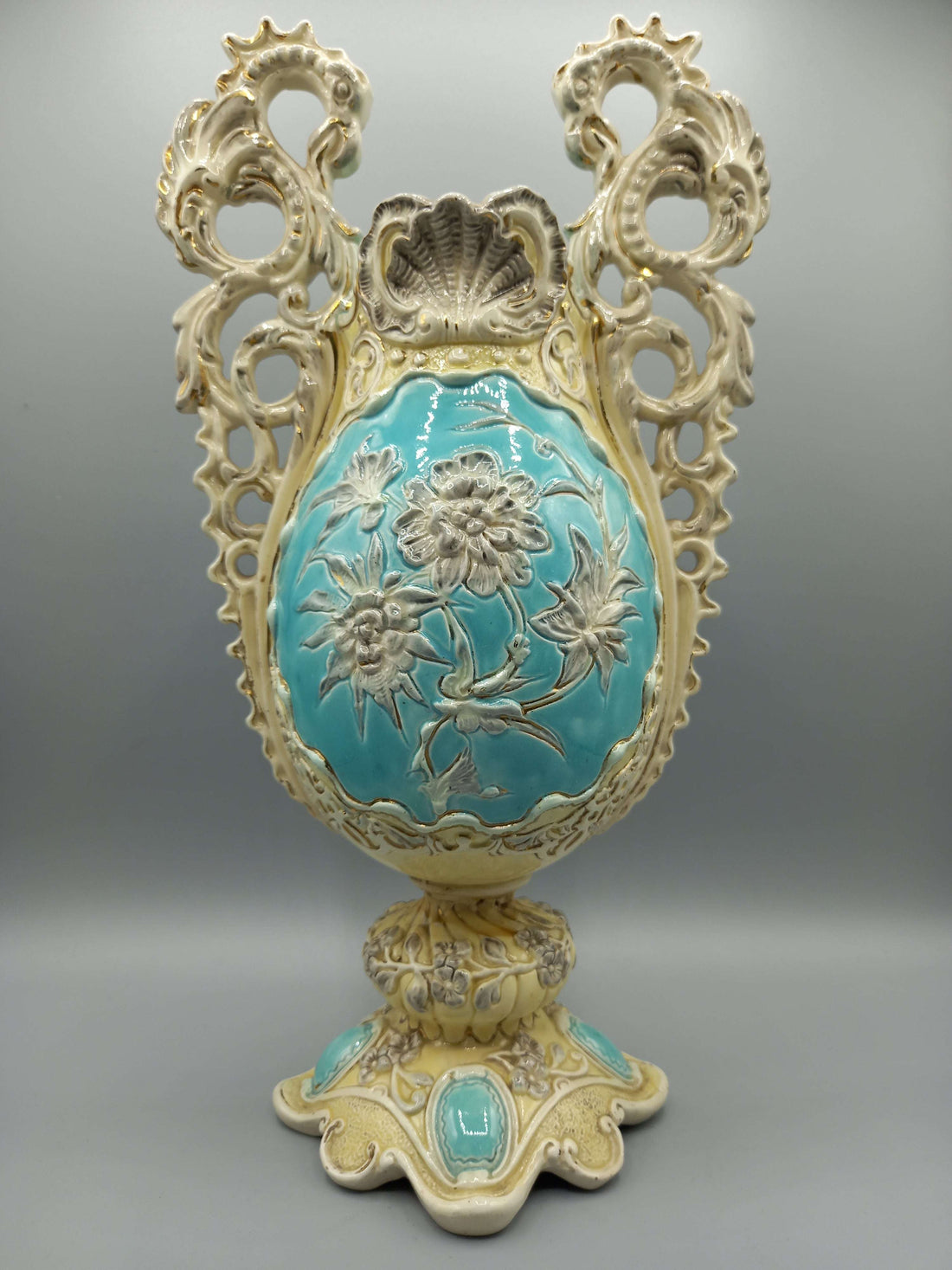 Jarron de ceramica esmaltado con detalles decorativos en tonos crema y turquesa, con relieves florales y diseño vintage ideal para decoración clásica.