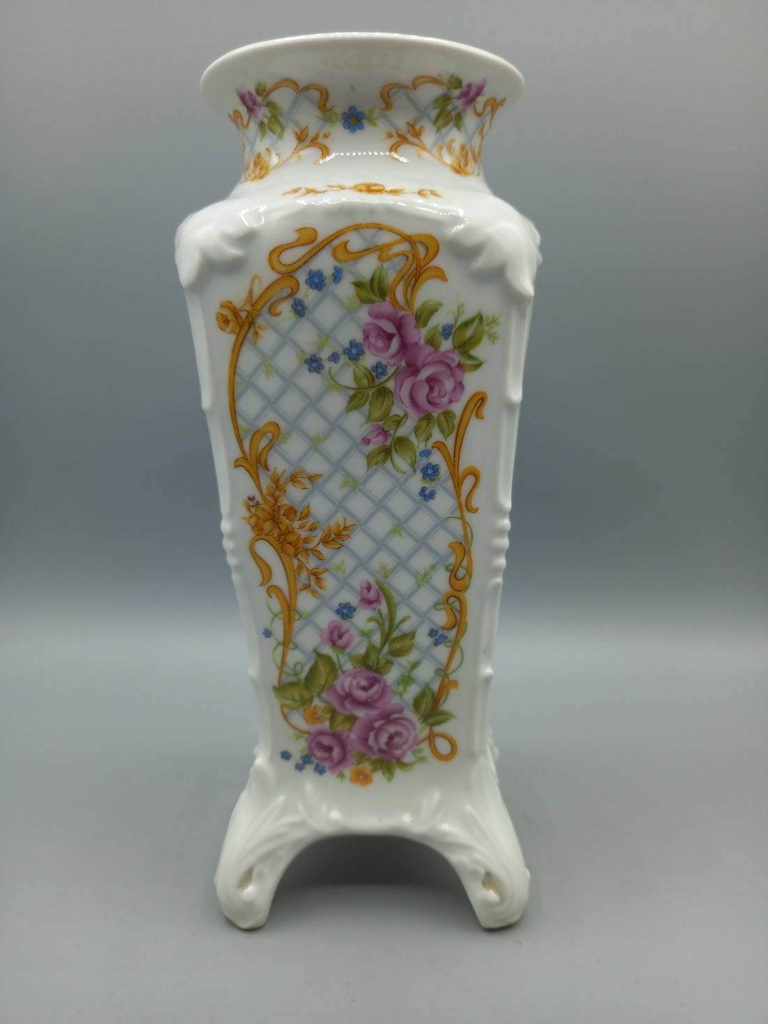 Jarrón de porcelana marca Sando con diseño floral en tonos dorados, rosas y azules. Decoración elegante para el hogar, ideal para interiores clásicos.