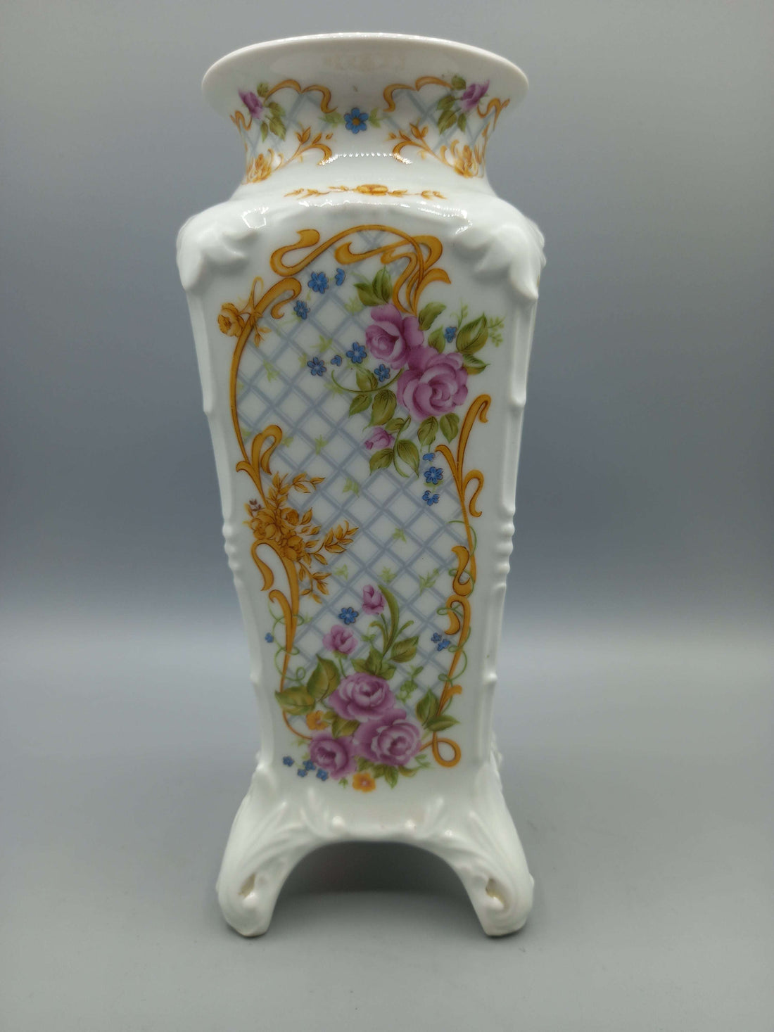Jarrón de porcelana marca Sando con diseño floral en tonos dorados, rosas y azules. Decoración elegante para el hogar, ideal para interiores clásicos.