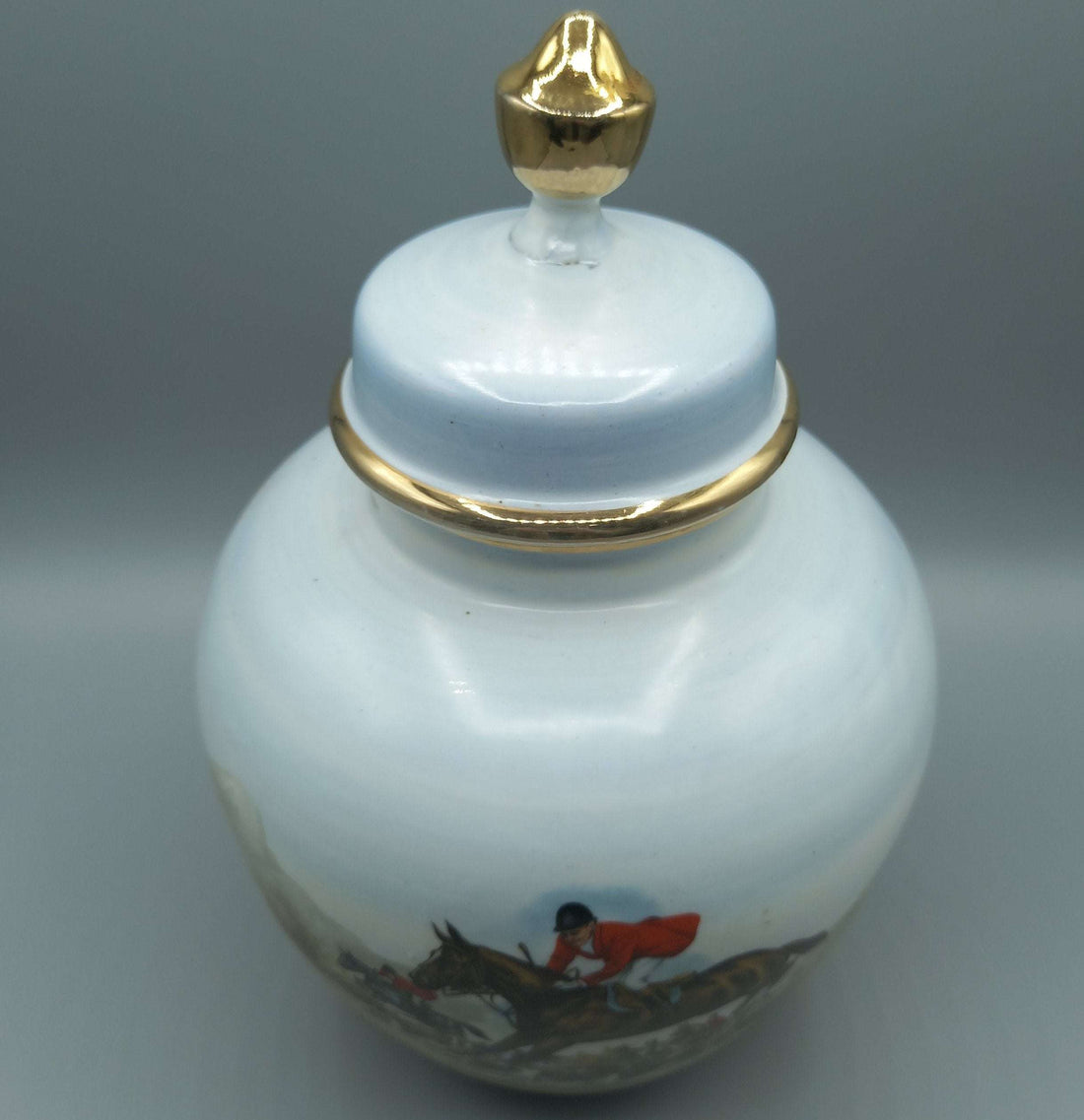 Tibor de porcelana pintado a mano con cacería inglesa, exclusivo, decorado con escena ecuestre y detalles dorados. Ideal para decoración clásica.
