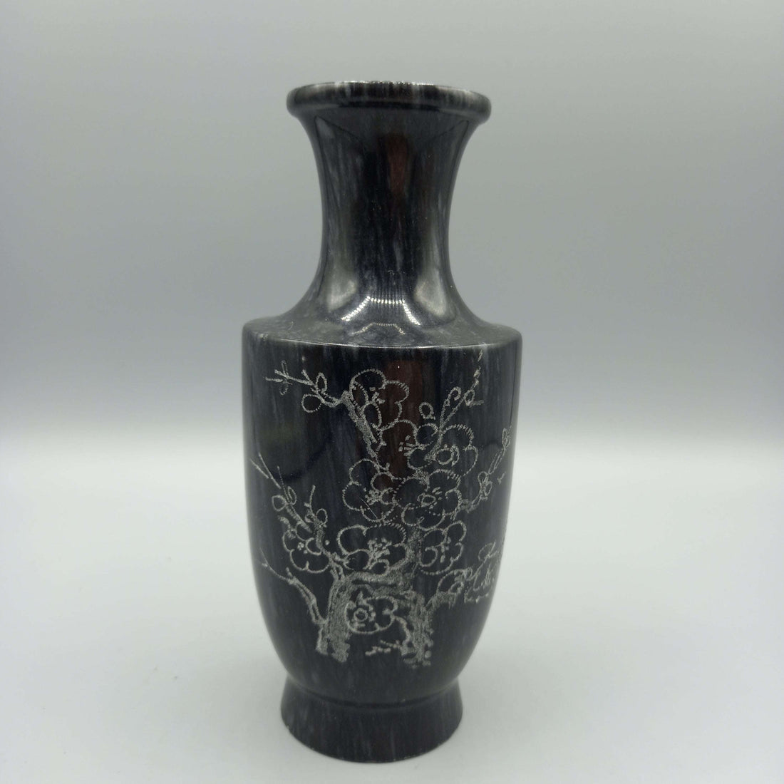 Florero de mármol tallado con diseño elegante de flores grabadas, ideal para decoración clásica en el hogar. Acabado artesanal en tono oscuro.