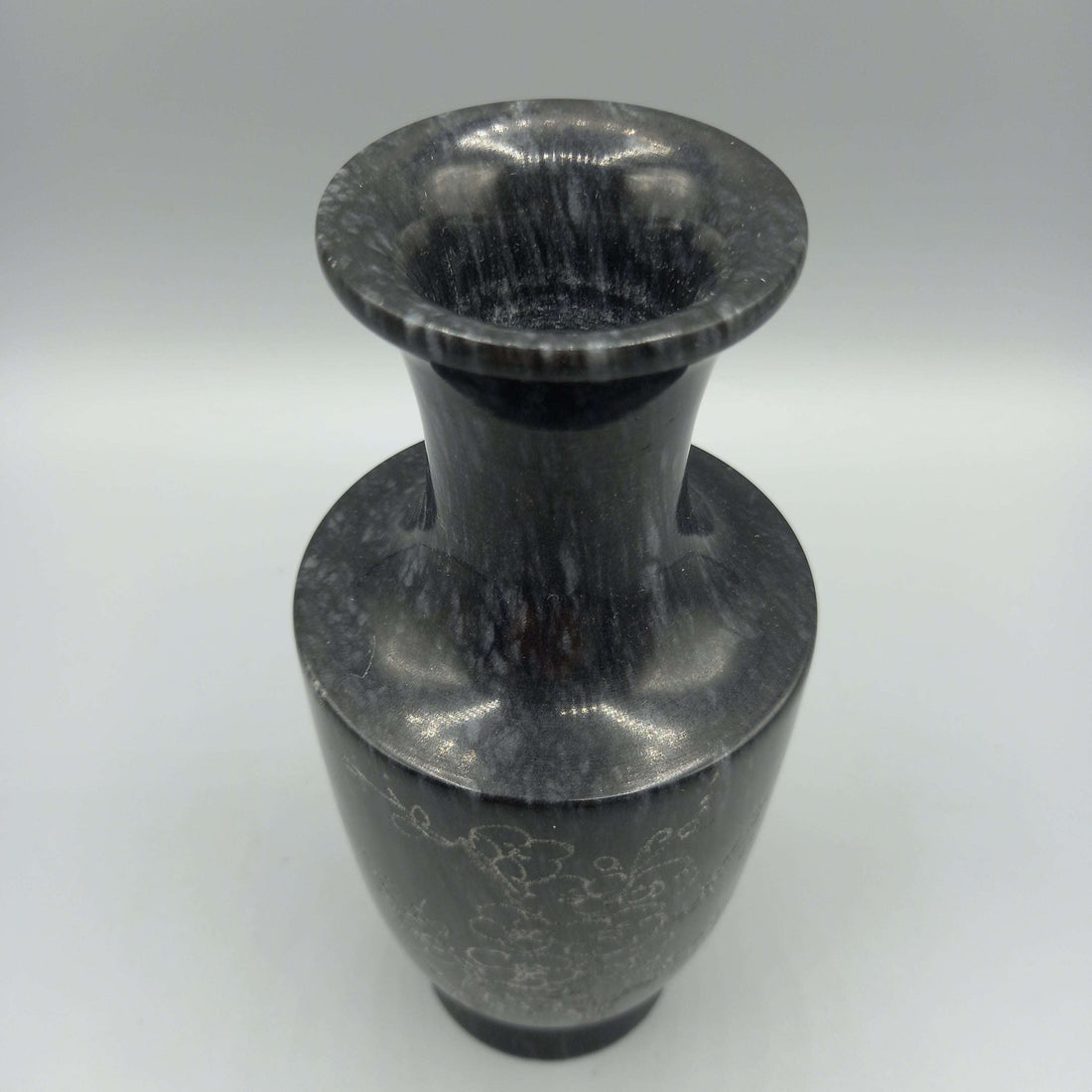 Florero de mármol tallado con diseño elegante de flores grabadas, ideal para decoración clásica en el hogar. Acabado artesanal en tono oscuro.