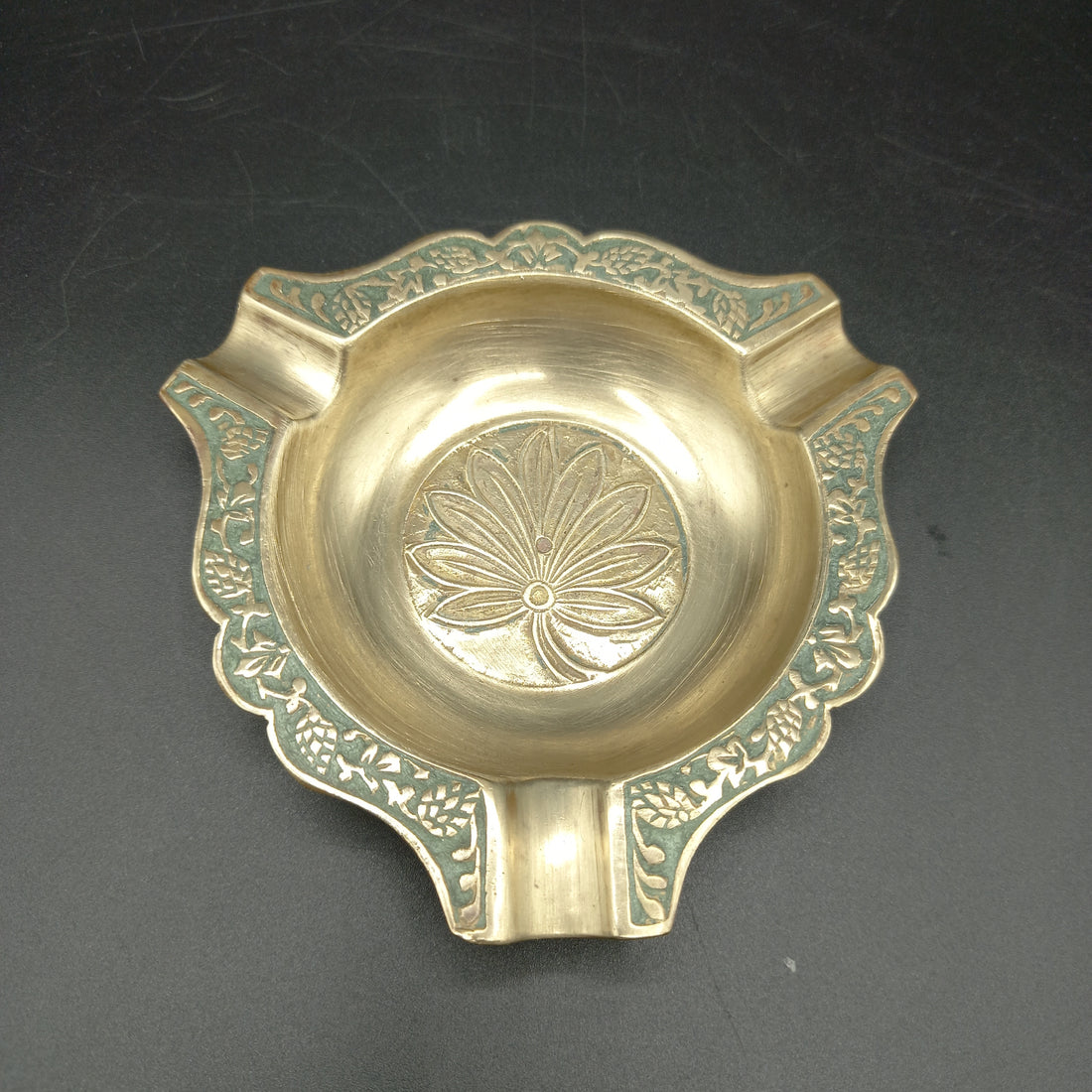 Vista superior del cenicero de metal, resaltando su diseño decorado con grabados florales.