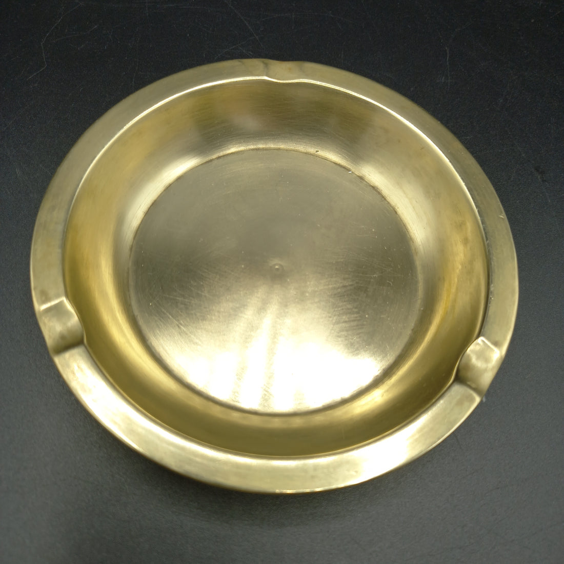 Vista superior del cenicero de metal dorado, resaltando su diseño elegante y su acabado pulido.