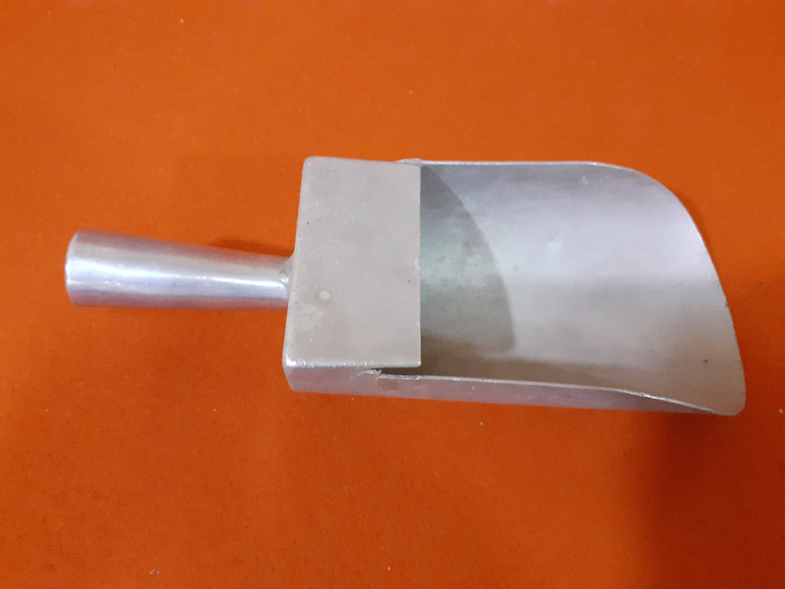 Cazo medida de aluminio para ultramarinos sobre fondo naranja, ideal para decoración vintage en cocinas o tiendas retro.