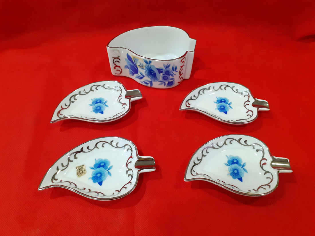 Juego completo de ceniceros de porcelana con decoración floral azul y detalles en hilo de plata sobre fondo rojo. Ideal para decoración elegante.