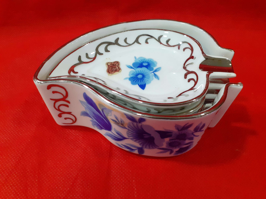 Juego completo de ceniceros de porcelana con decoración floral azul y detalles en hilo de plata sobre fondo rojo. Ideal para decoración elegante.