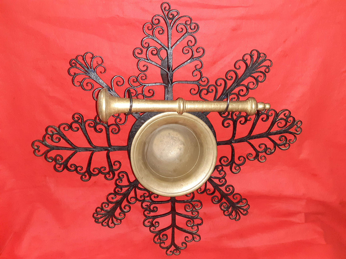 Mortero con filigranas antiguas de metal sobre fondo rojo, ideal para decoración de pared única en estilo vintage. Pieza exclusiva de almirez colgante.