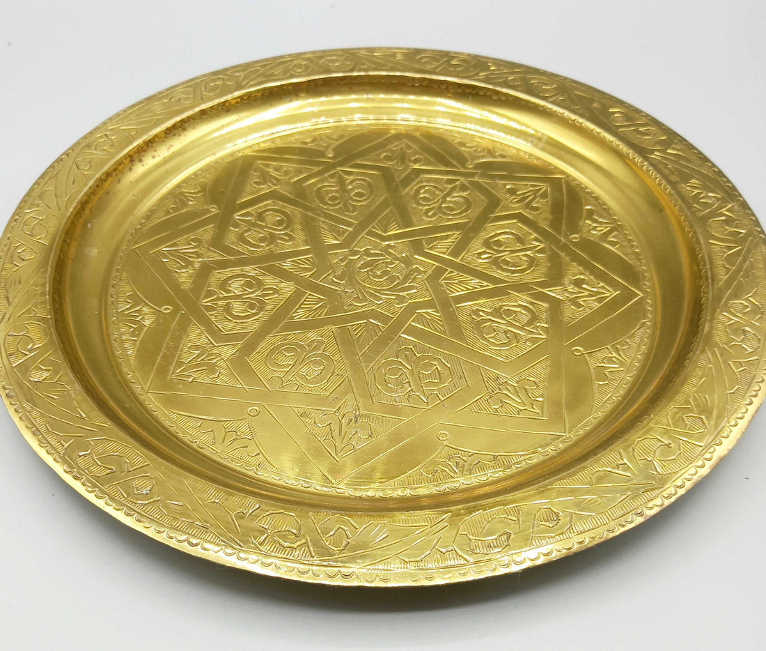 Plato repujado de metal dorado con diseño geométrico exclusivo, ideal para decoración elegante en el hogar. Excelente calidad artesanal.