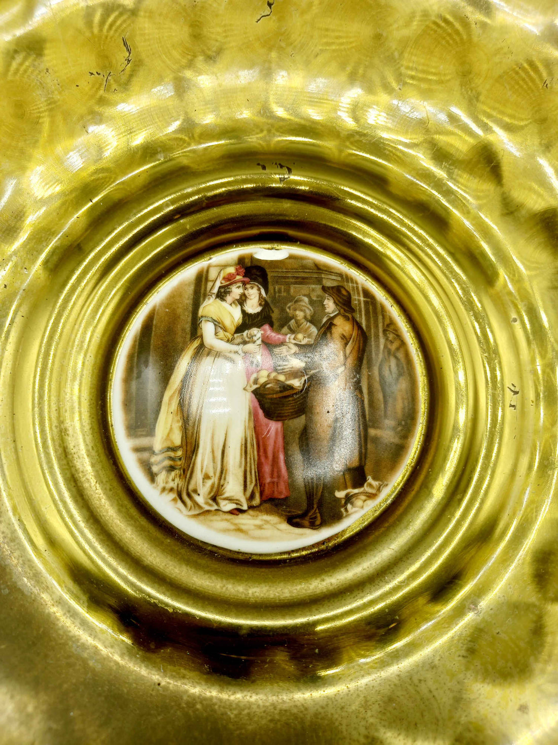 Plato de metal esmaltado, elegante y de excelente calidad con acabado dorado texturizado y escena clásica pintada al centro, ideal para decoración.