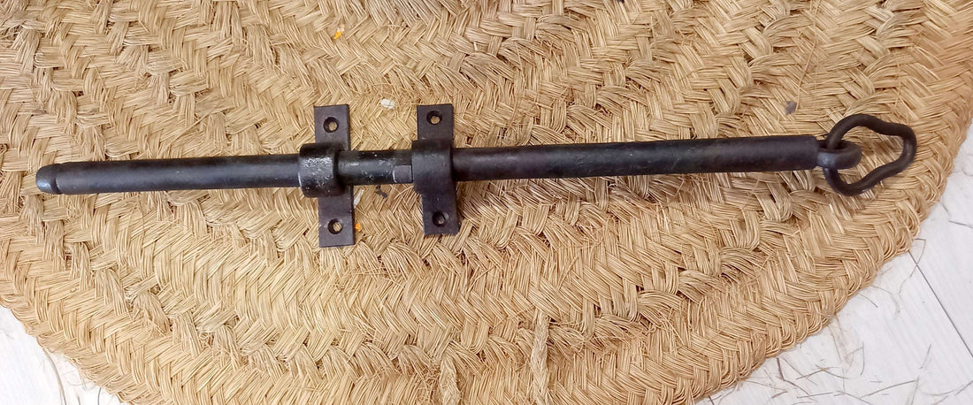 Pestillo de puerta antiguo de hierro forjado con diseño clásico, ideal para decoración rústica y seguridad en puertas de madera.