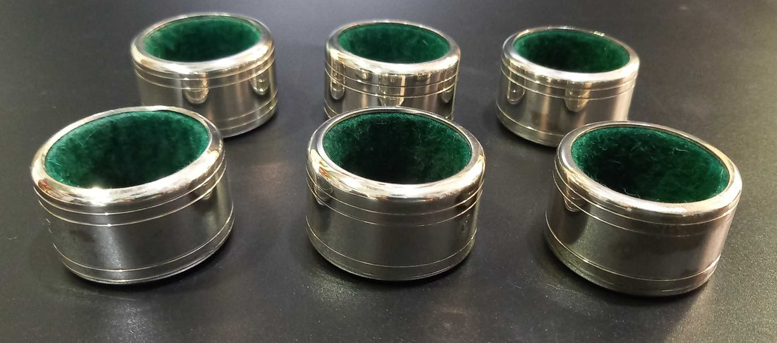 Set de 6 servilleteros de metal plateado con interior forrado en terciopelo verde, numerados del 1 al 6. Ideal para decoración de mesa elegante.