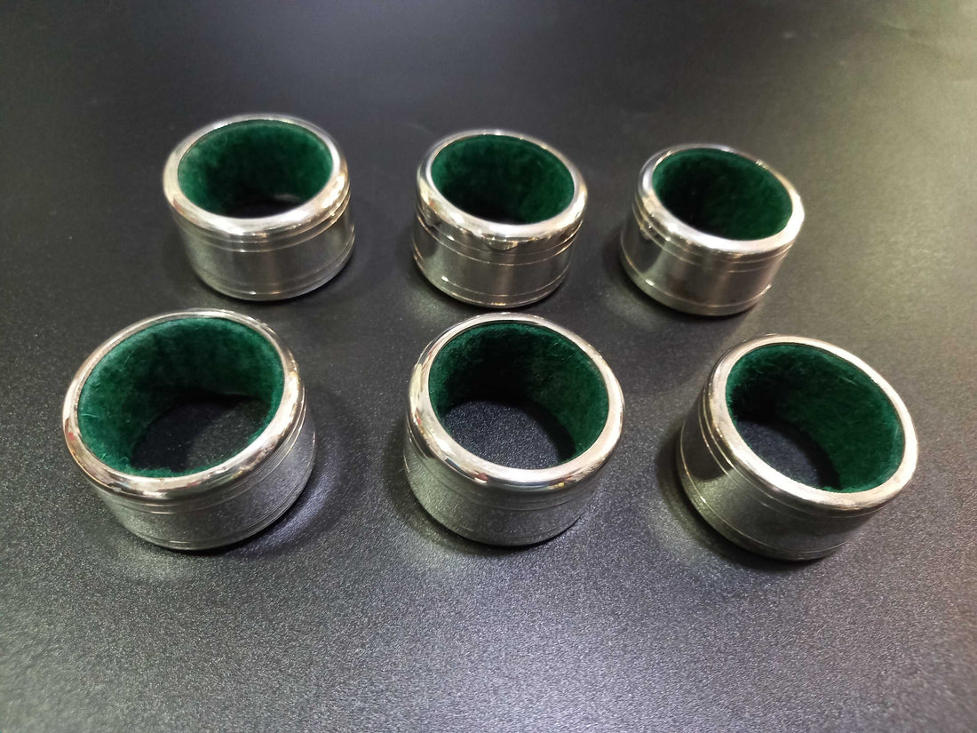 Set de 6 servilleteros de metal plateado con interior forrado en terciopelo verde, numerados del 1 al 6. Ideal para decoración de mesa elegante.