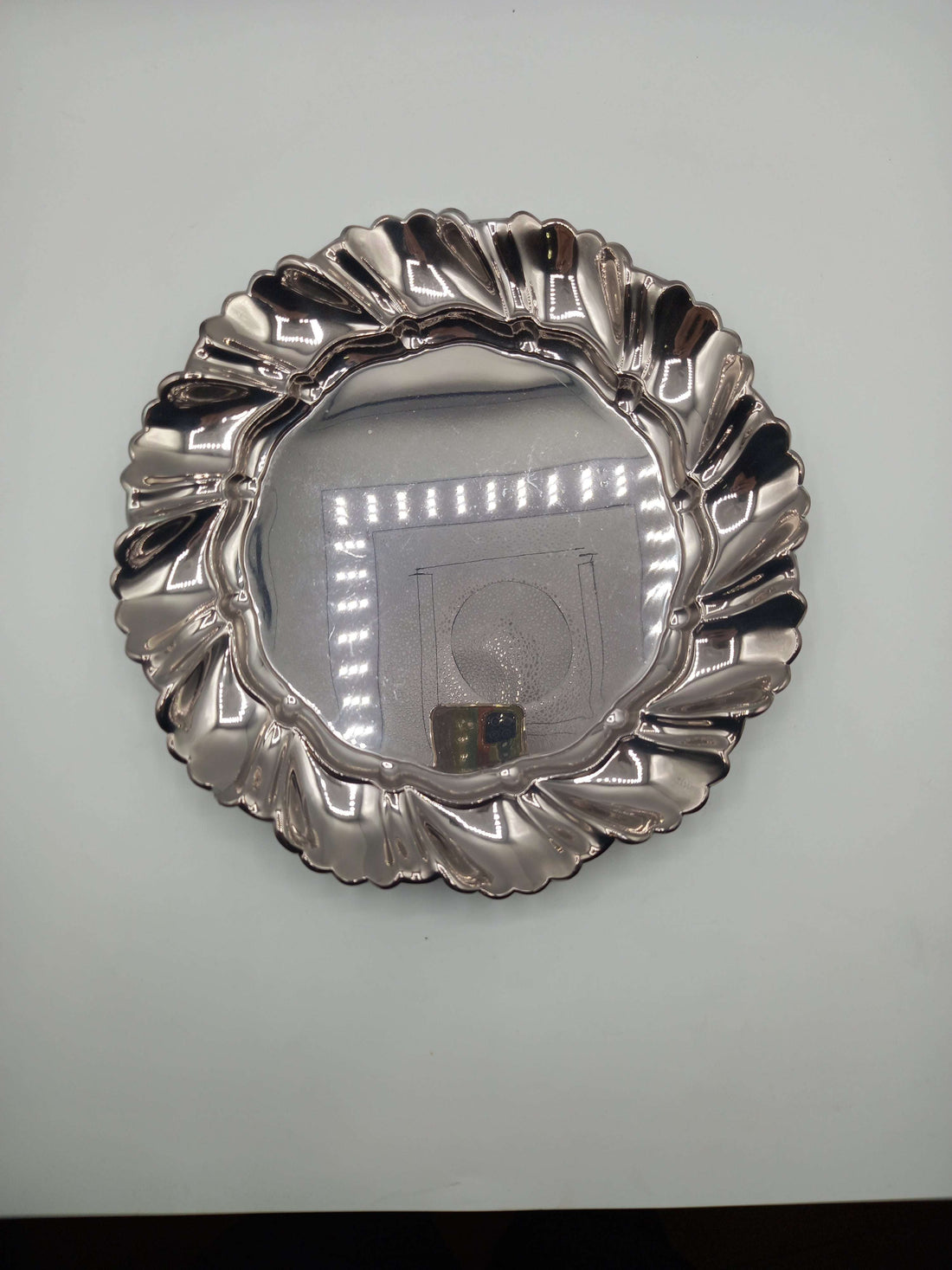 Elegante plato de metal plateado con borde ondulado, ideal para decoración refinada en el hogar o eventos especiales.