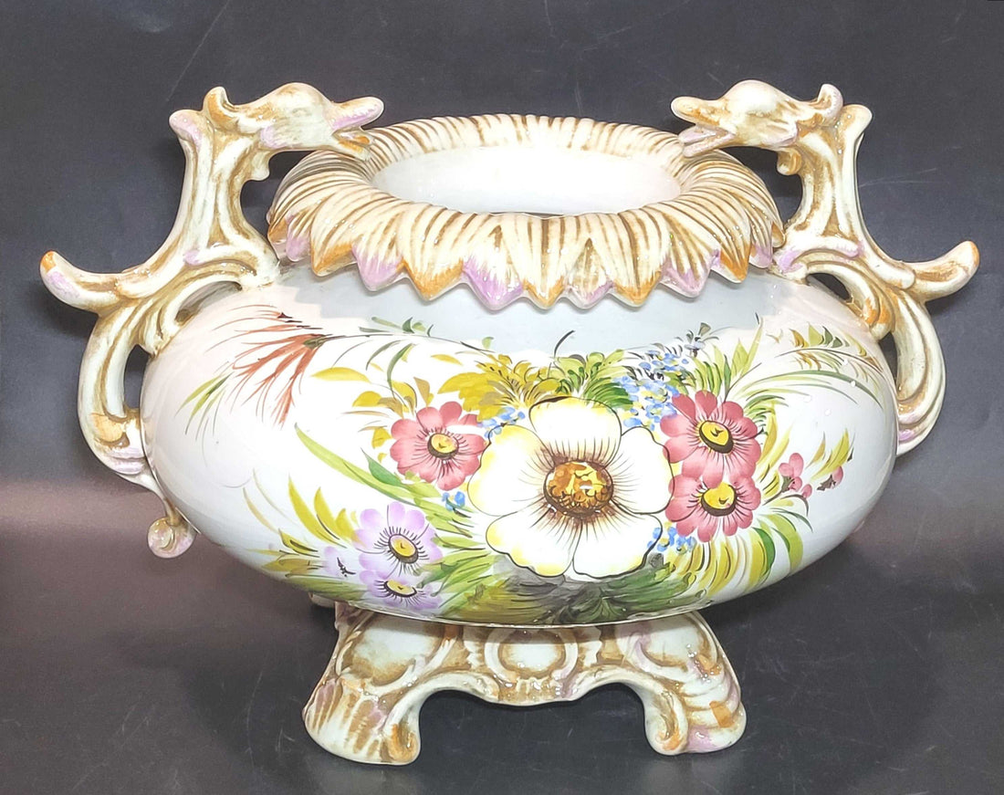 Centro de mesa elegante y antiguo de porcelana pintado a mano con asas ornamentales y flores coloridas. Ideal para decoración de interiores clásicos.