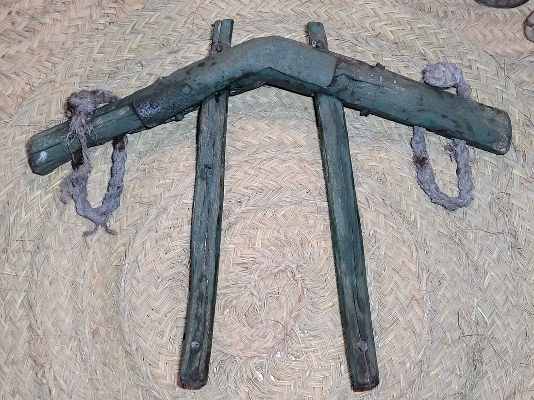 Yugo de costillas en madera de encina con refuerzos de hierro sobre fondo de esparto. Ideal para decoración rústica en hogar o jardín.