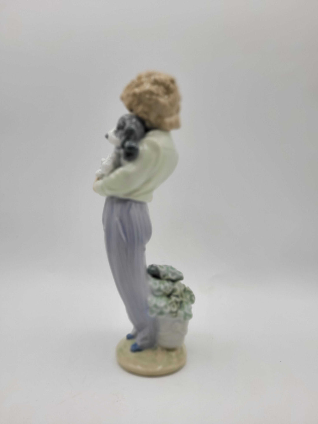 Figura Lladró 'Perrito Convaleciente' de 1989 en porcelana, muestra a un niño con pijama a rayas sosteniendo un perrito enfermo. Edición limitada ideal para decoración de interiores.