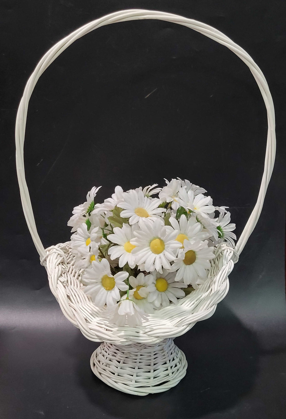 Canasto de mimbre blanco con margaritas blancas, estilo vintage ideal para decoración de interiores o eventos especiales en el hogar.