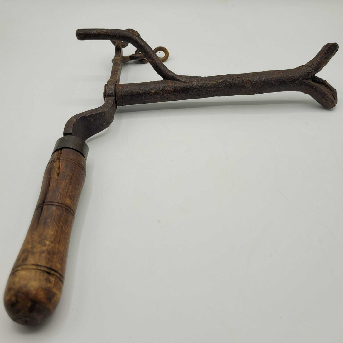 Maneta antigua de cancela con mango de madera y estructura de hierro oxidado, ideal para apertura remota de portones con poleas.