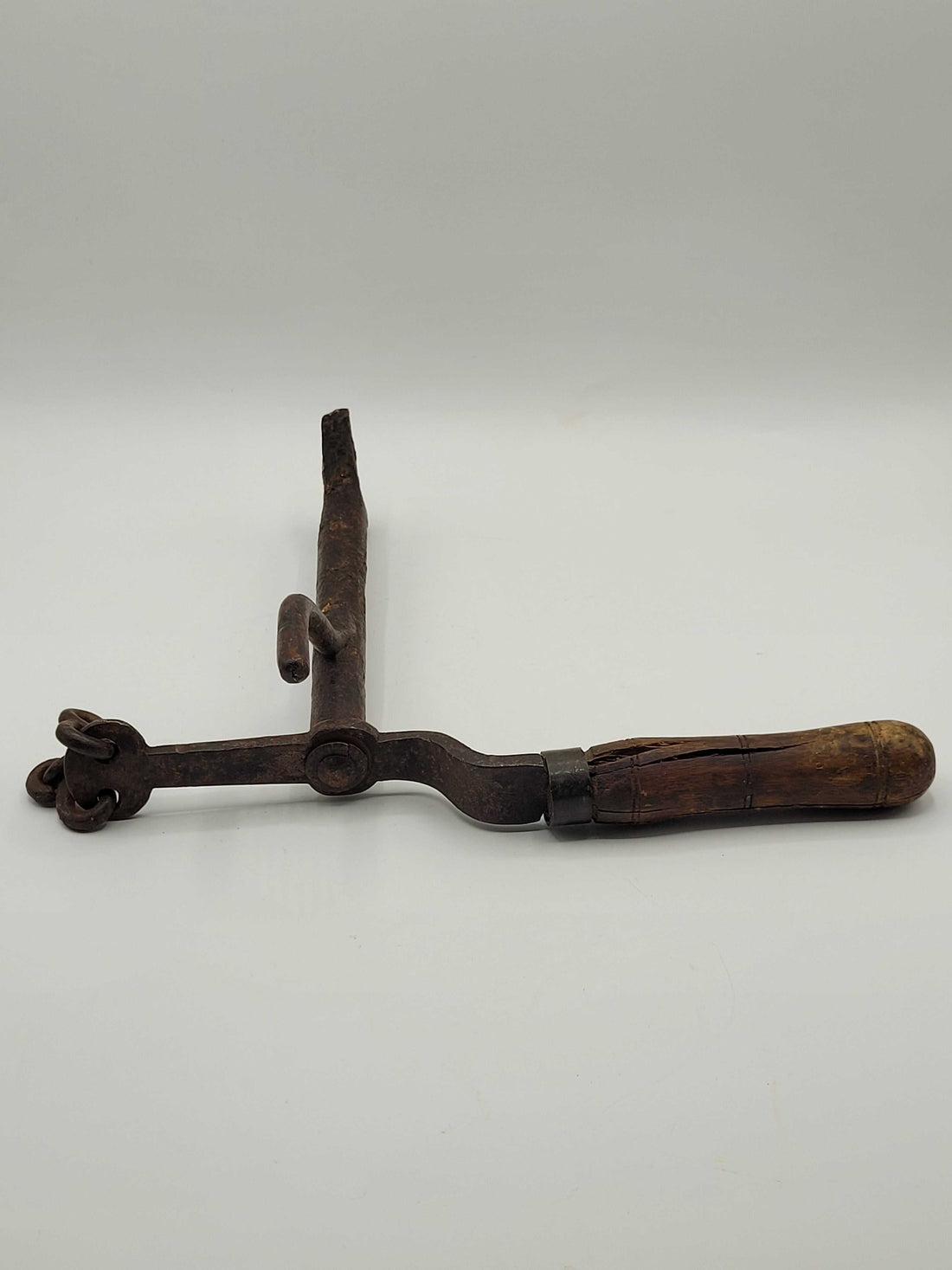 Maneta antigua de cancela con mango de madera y estructura de hierro oxidado, ideal para apertura remota de portones con poleas.