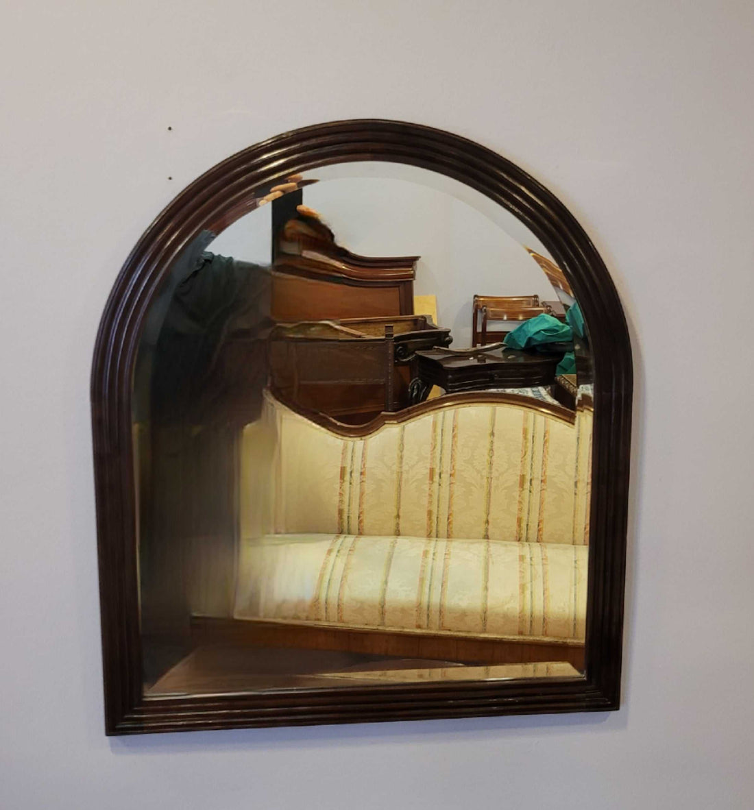 Espejo antiguo de pared con marco de caoba tallada, forma arqueada y cristal biselado, ideal para decoración vintage en interiores clásicos.