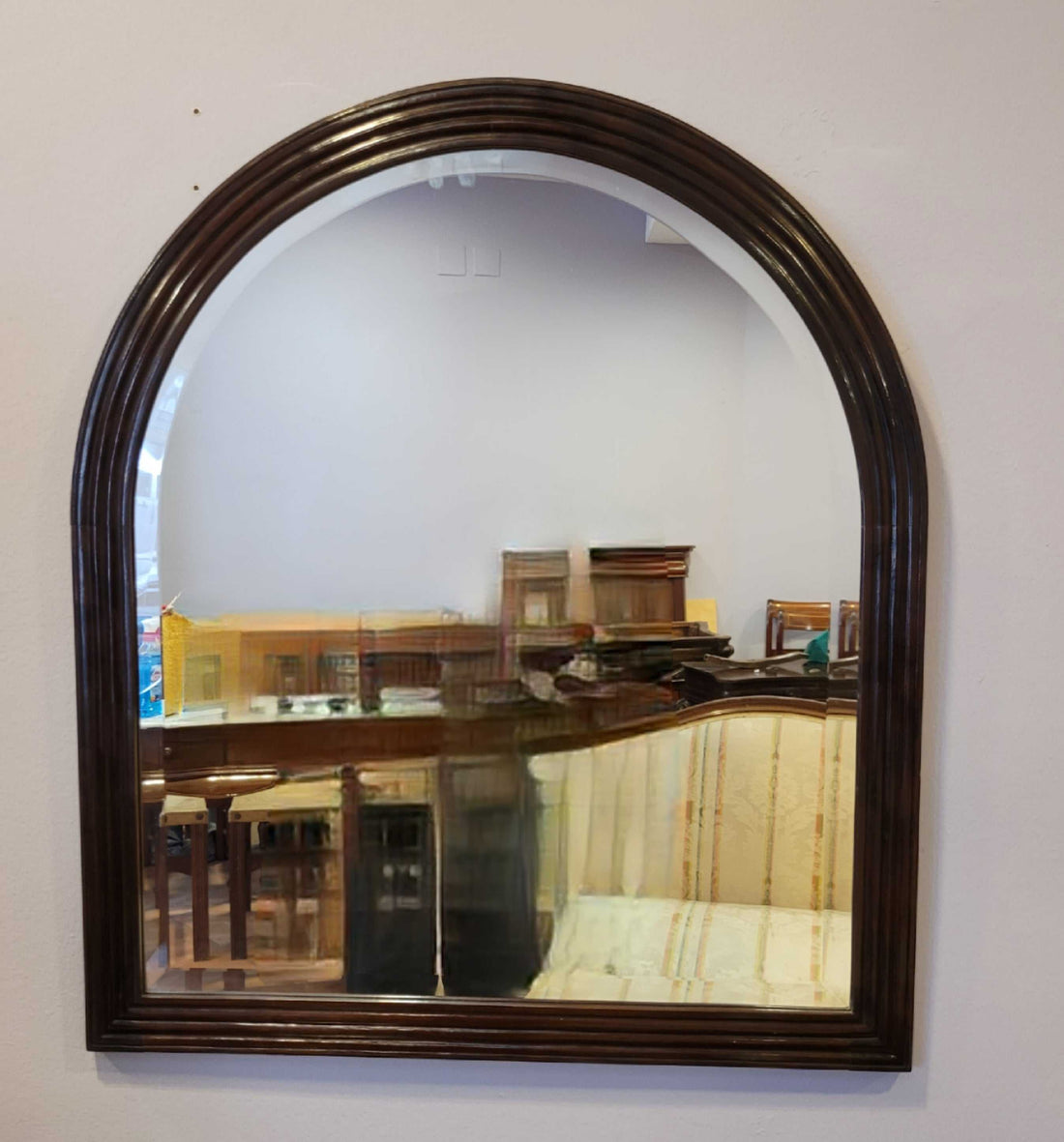 Espejo antiguo de pared con marco de caoba tallada, forma arqueada y cristal biselado, ideal para decoración vintage en interiores clásicos.