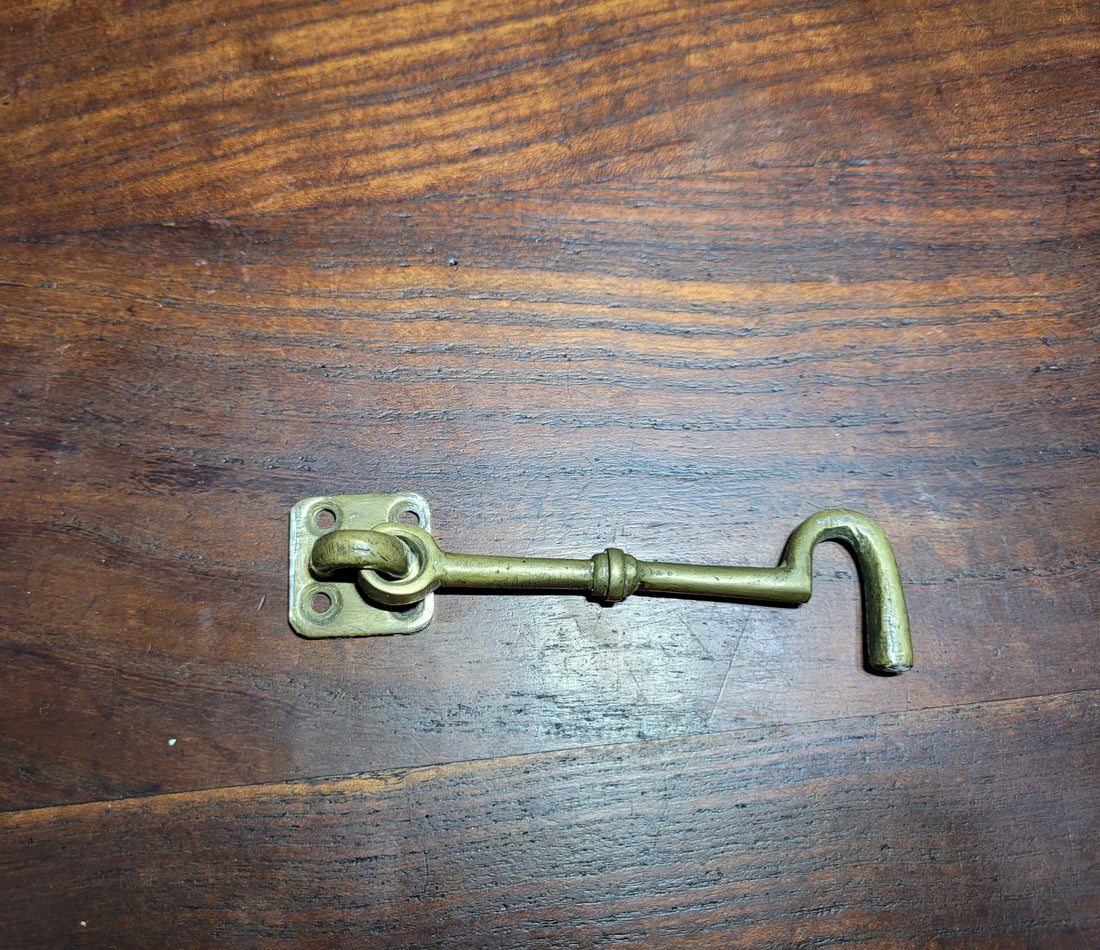 Aldabilla de metal vintage sobre superficie de madera, ideal para puertas y ventanas, combina seguridad y estilo único.