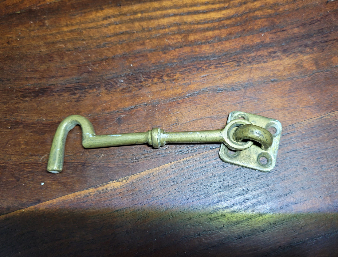 Aldabilla de metal vintage sobre superficie de madera, ideal para puertas y ventanas, combina seguridad y estilo único.