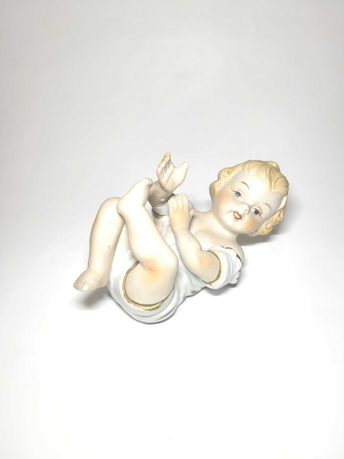 Esta imagen de niño, fabricada en porcelana de Biscuit policromado, es un artículo exquisito que destaca por su belleza y detallada fabricación. 