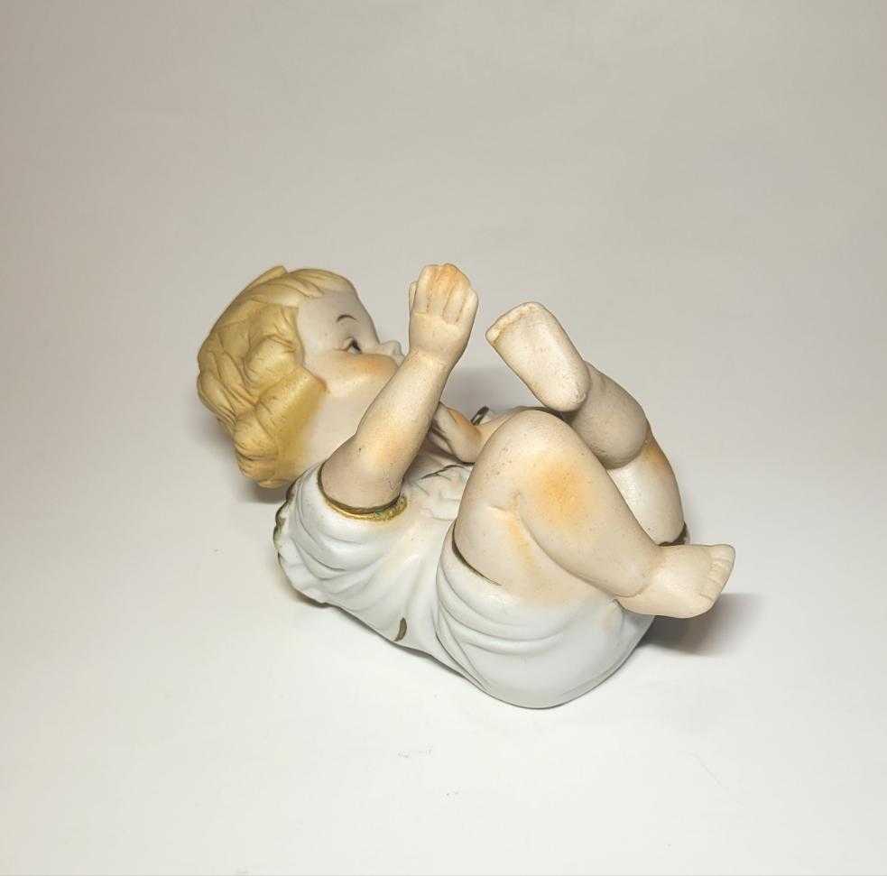 Esta imagen de niño, fabricada en porcelana de Biscuit policromado, es un artículo exquisito que destaca por su belleza y detallada fabricación. 
