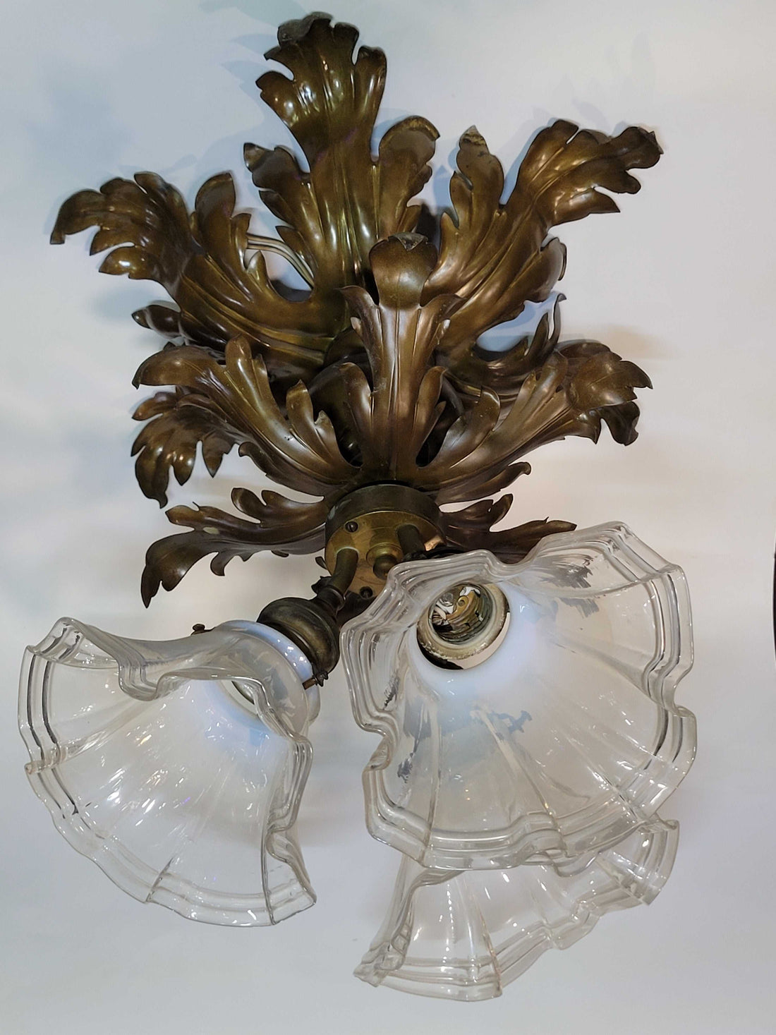 Lámpara de techo antigua de metal con hojas ornamentales y dos tulipas de cristal ondulado, ideal para decoración vintage de interiores.