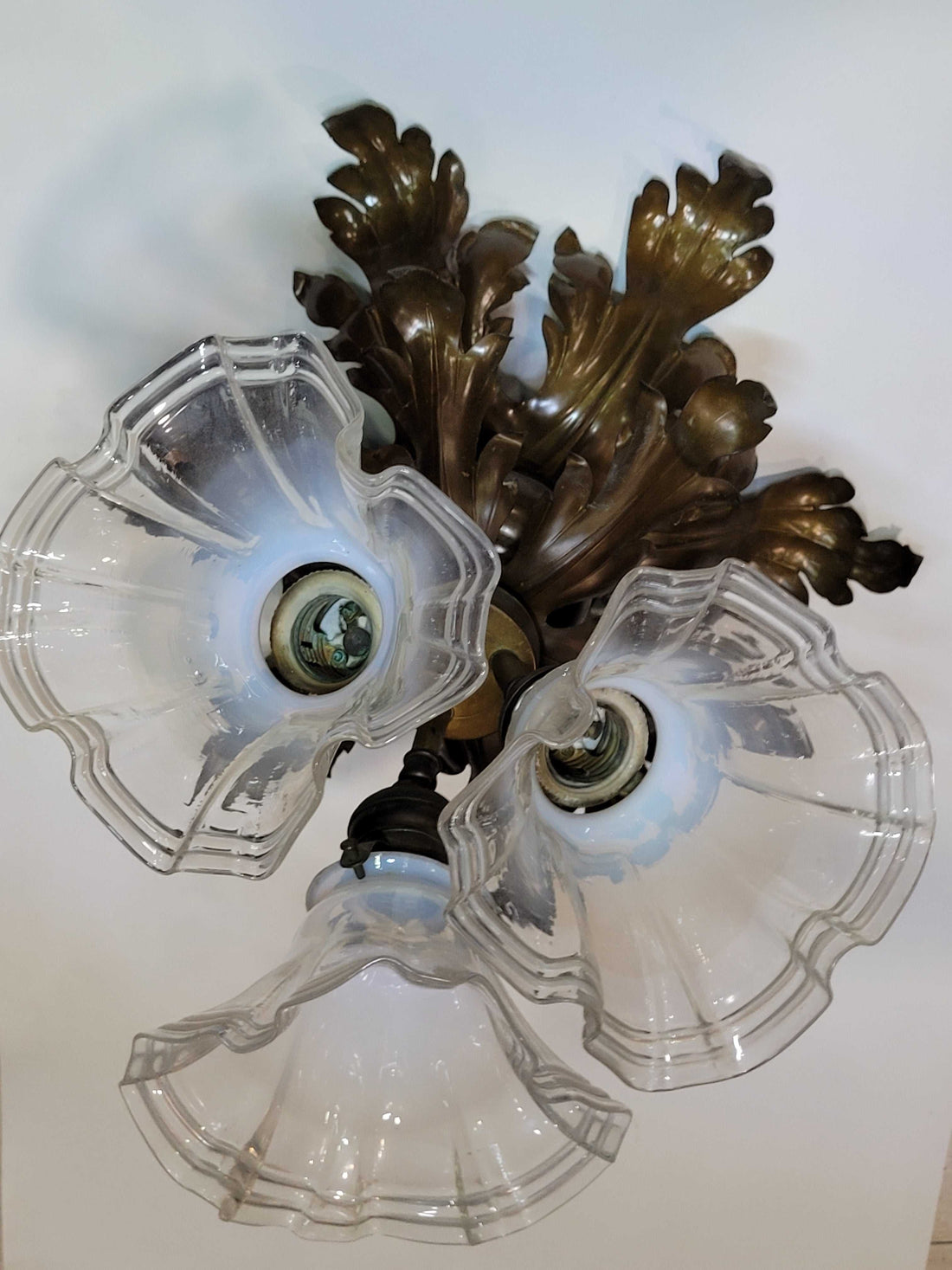 Lámpara de techo antigua de metal con hojas ornamentales y dos tulipas de cristal ondulado, ideal para decoración vintage de interiores.