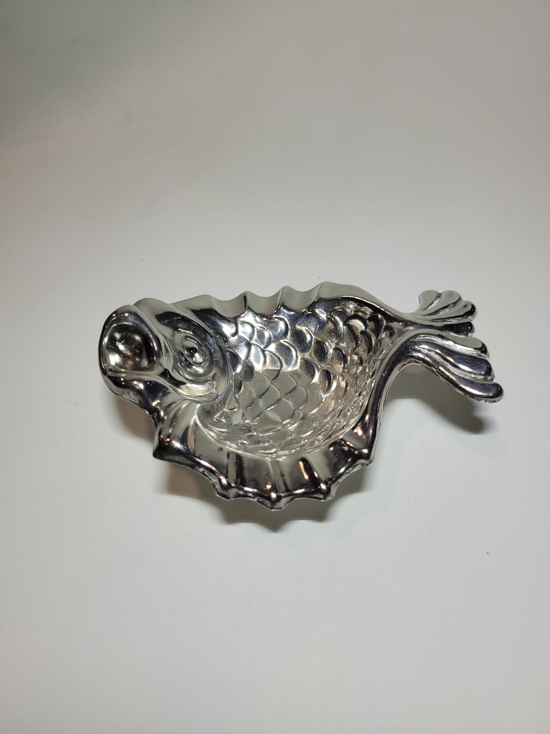 Cenicero de metal plateado en forma de pez con diseño elegante y detalles escamados, ideal para decoración vintage.