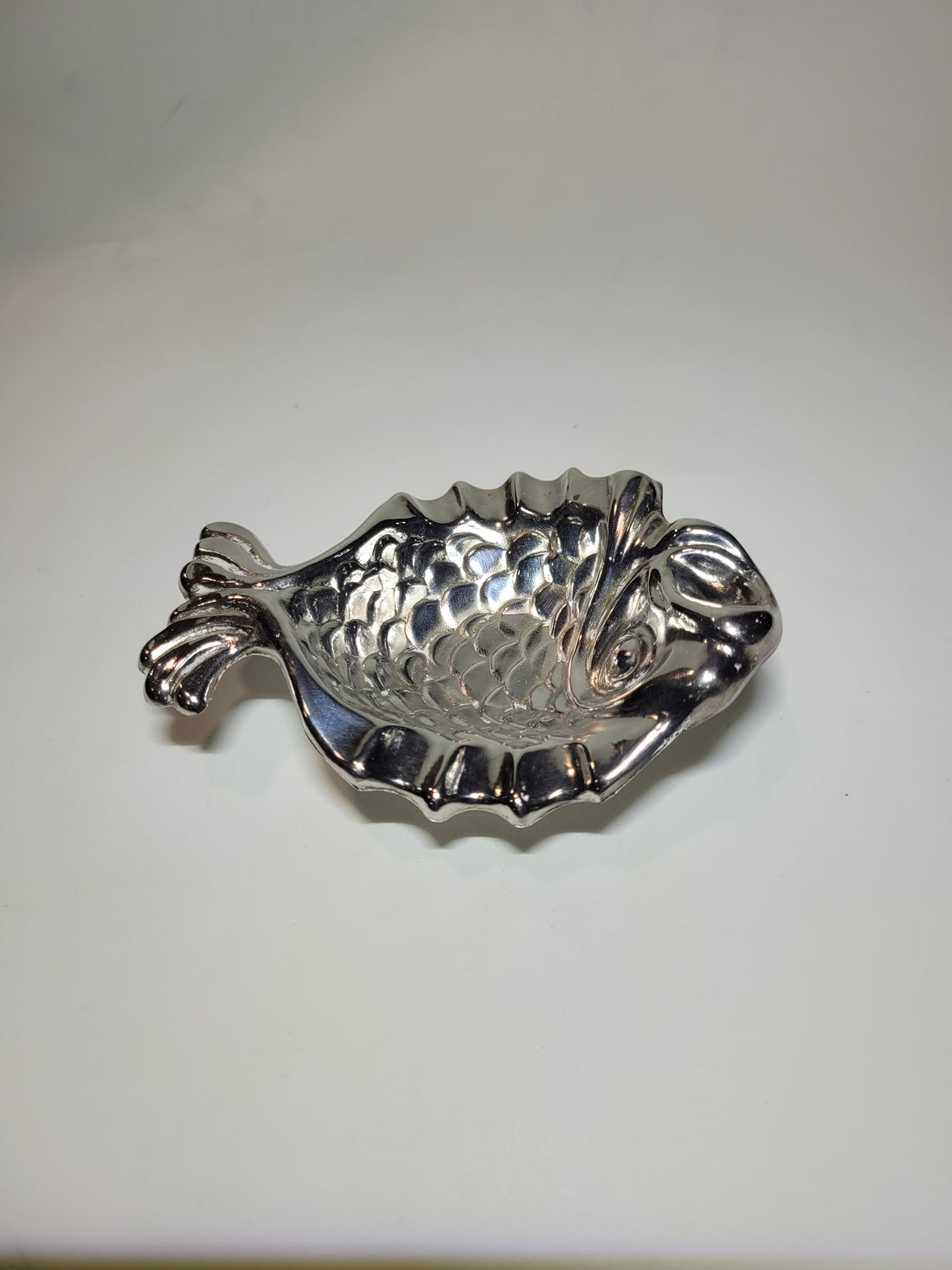 Cenicero de metal plateado en forma de pez con diseño elegante y detalles escamados, ideal para decoración vintage.