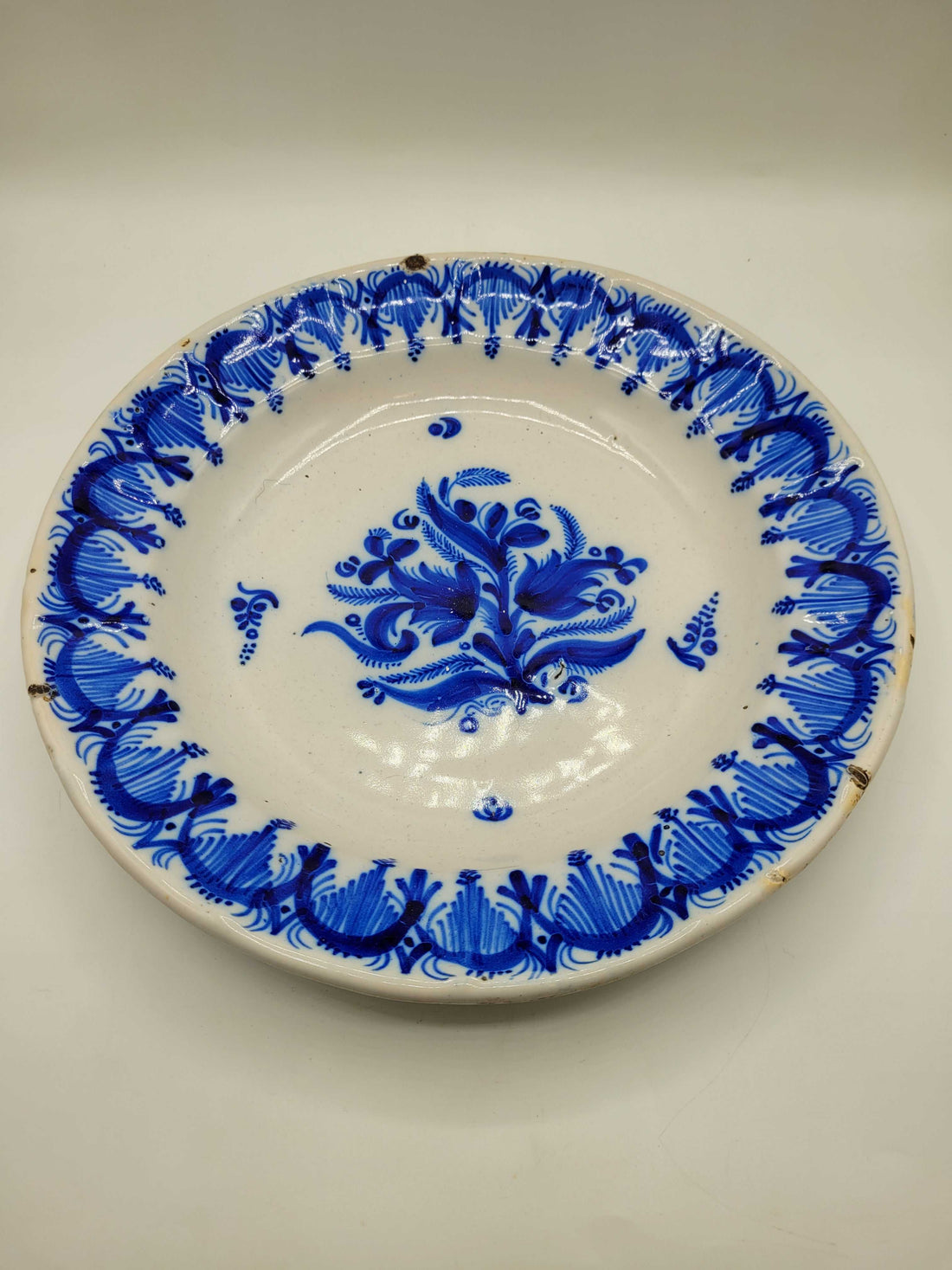 Plato antiguo decorado con flor central y guirnalda azul