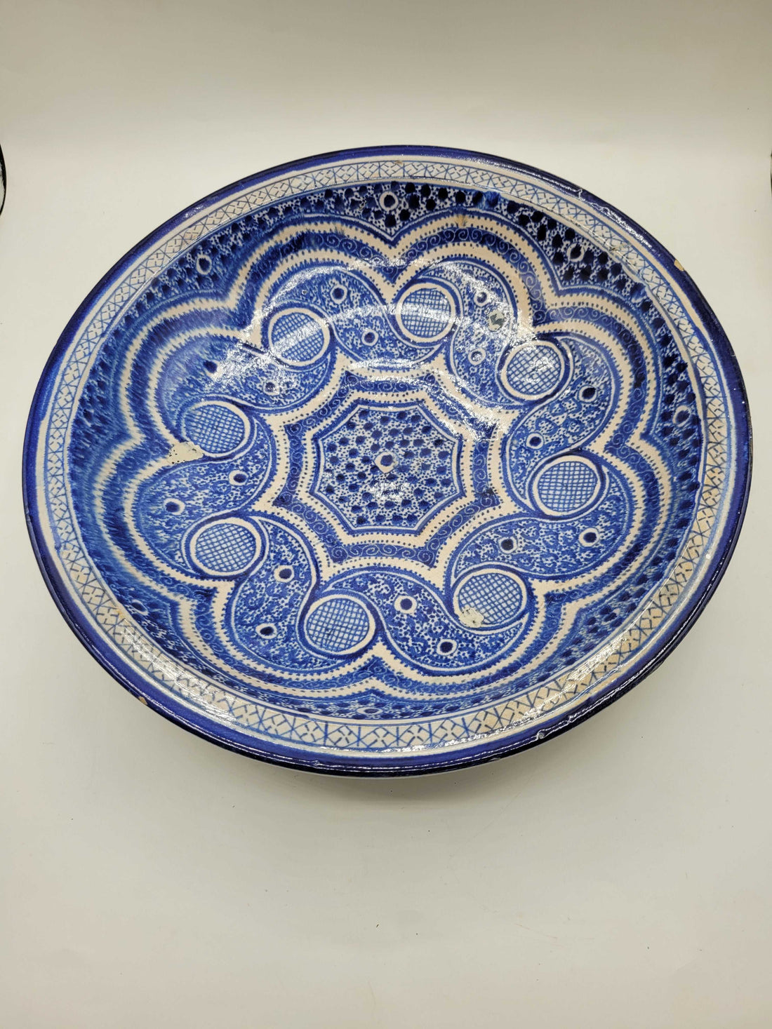 Plato árabe antiguo de cerámica con decoración simétrica pintada a mano.