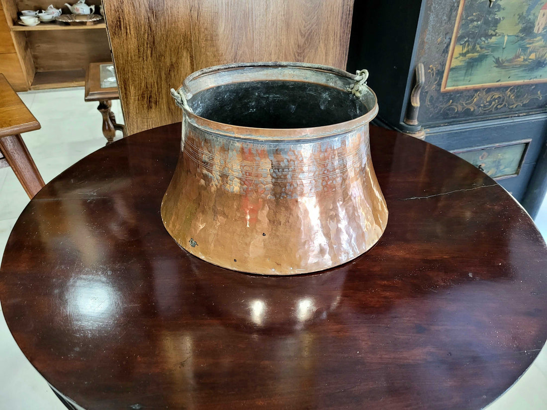 Caldero de cobre antiguo de cuerpo redondeado con asa lateral robusta y pátina natural.

