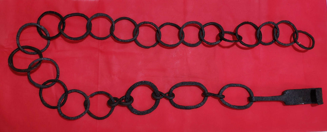 Cadena en la chimenea para colgar calderos de hierro forjado, estilo antiguo, sobre fondo rojo. Ideal para decoración rústica o vintage.